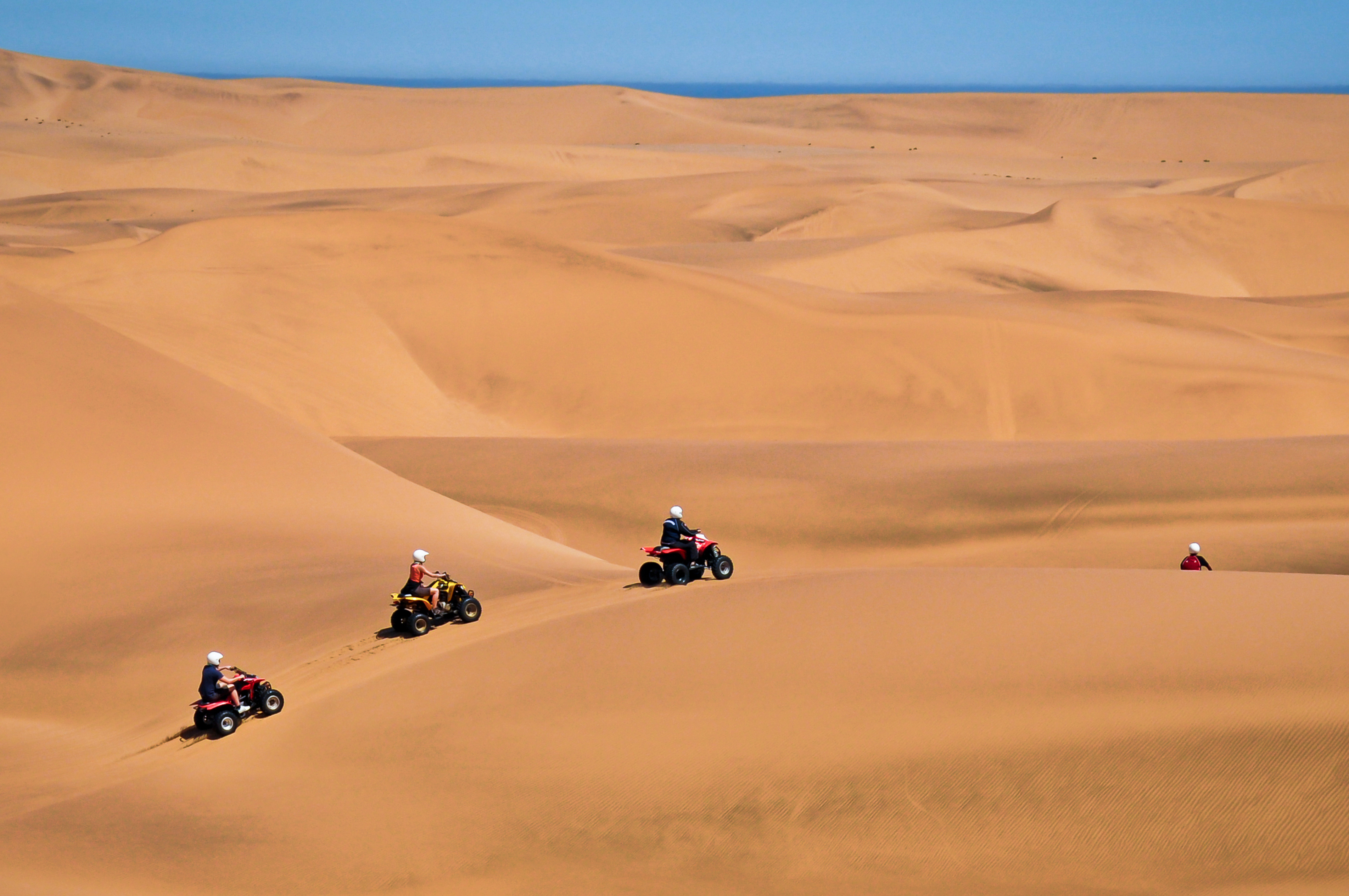 Four quadbike riders crossing the Namib dunes