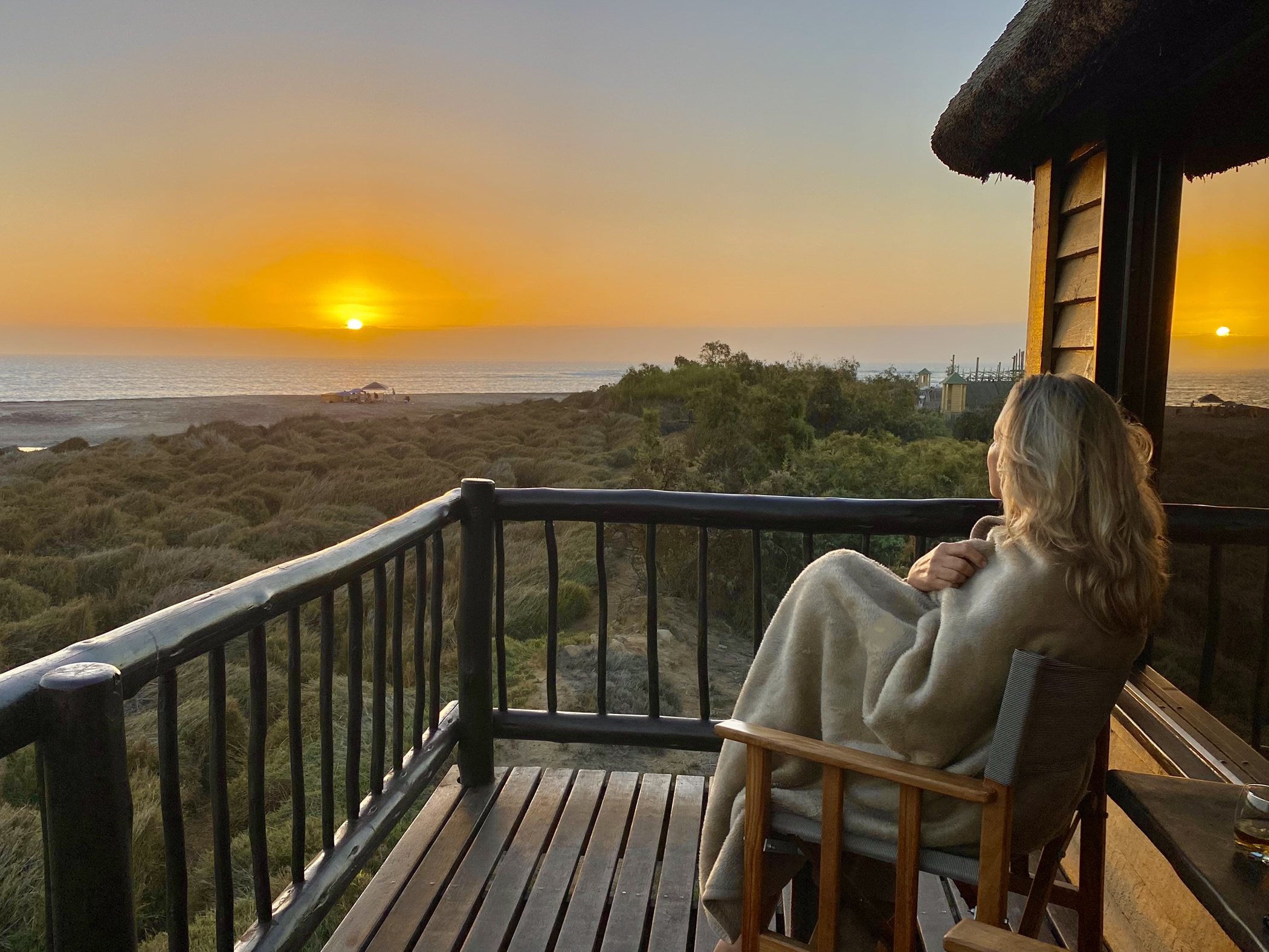 Guest enjoying sunrise from a private balcony above the lagoon