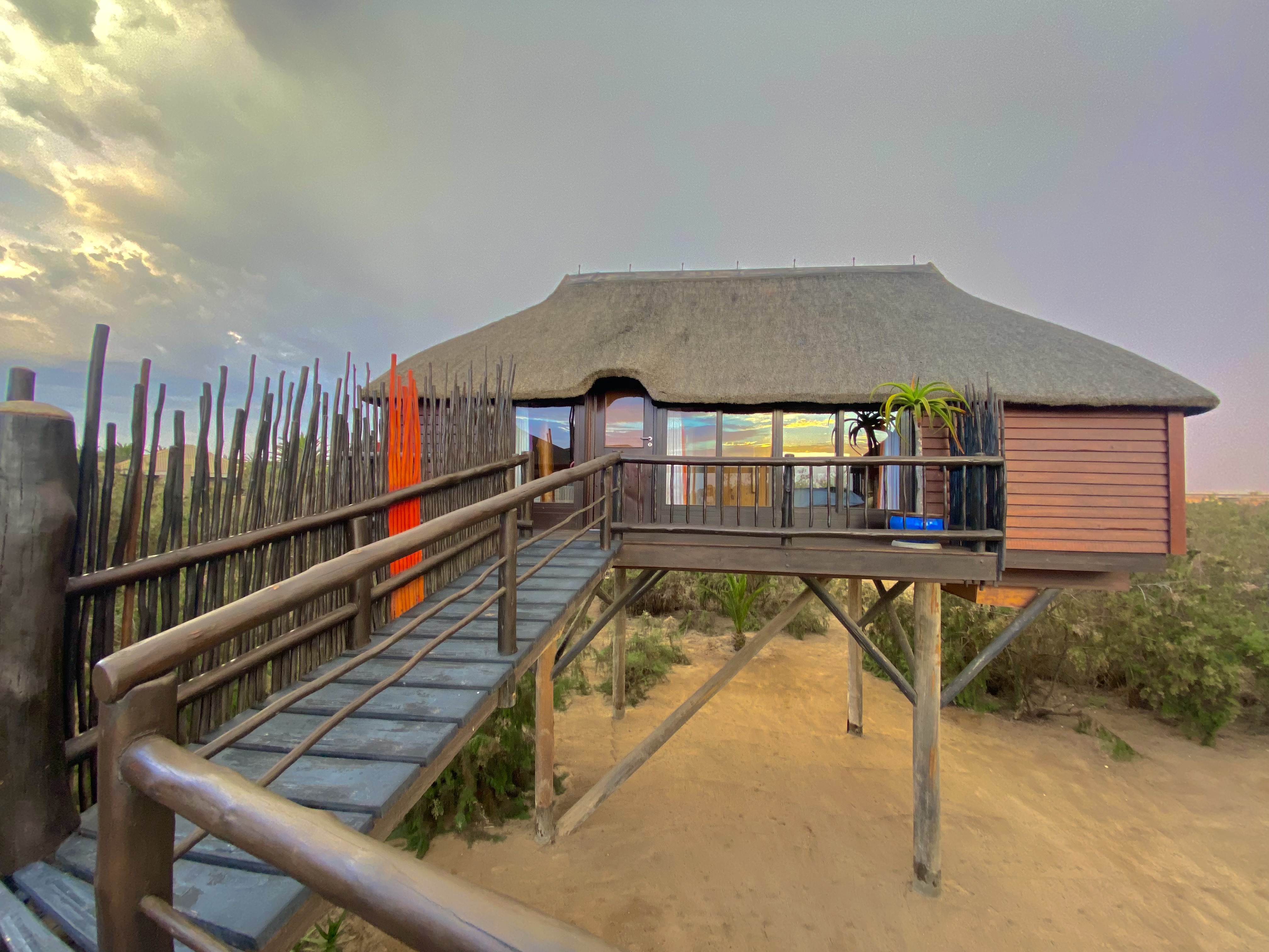 Family Bungalow exterior with a raised wooden walkway and sunset reflected in the windows