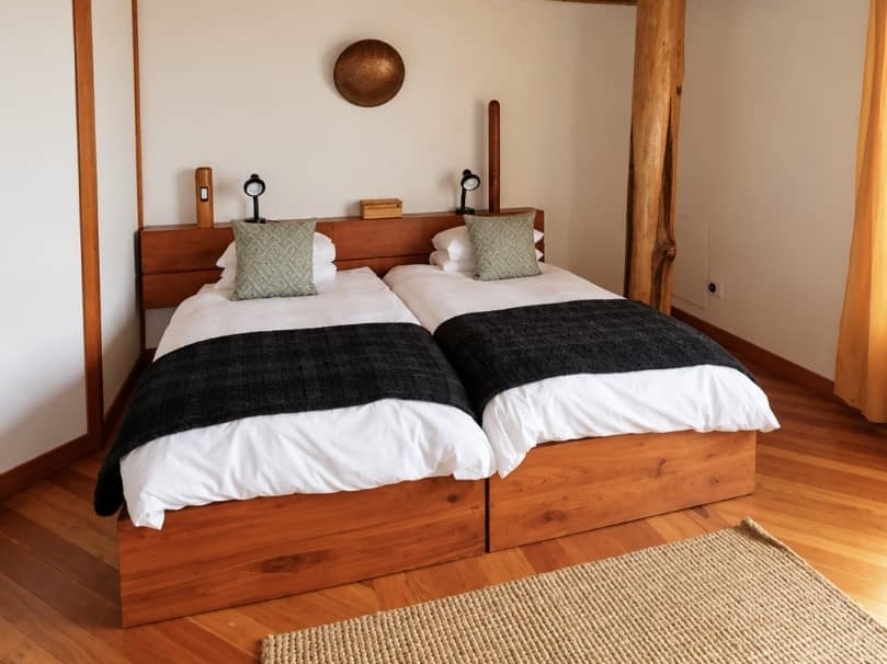 Villa twin bedroom with dark throws and timber details